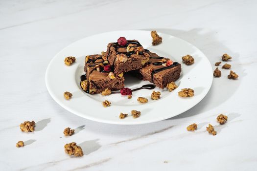 Chocolate brownie squares with walnut pieces, chocolate threads and granola. Natural, healthy food concept. High view.
