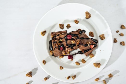 Chocolate brownie squares with walnut pieces, chocolate threads and granola. Natural, healthy food concept. Top view. copy space.