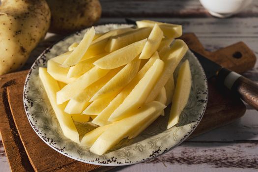 Dish with raw cane potatoes to make french fries. Chopped or high view. close-up.