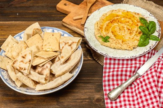 High view of a plate of homemade hummus with pita bread and crackers. Fresh, healthy and natural food concept. Copy space.