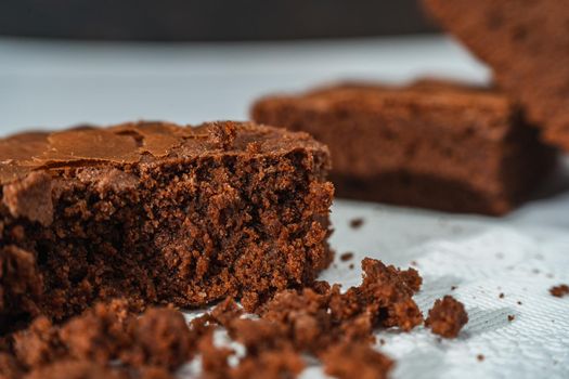 A cubes of chocolate brownies on a white plate on a marble table. Close up shot.