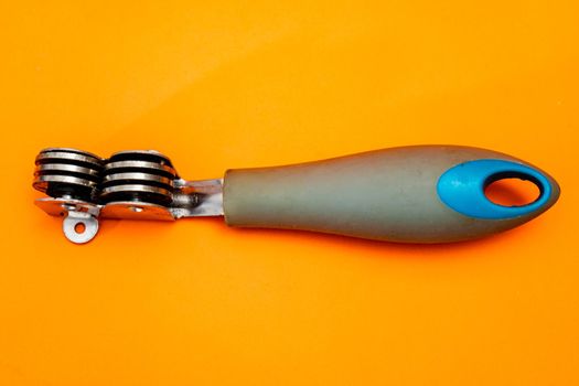 Knife sharpener isolated on an orange background. Inexpensive non-professional kitchen utensil.