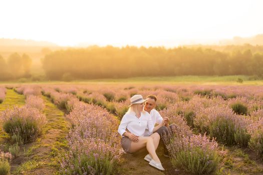 Handsome man with attractive woman lying down on fresh lavender field, enjoying each other, romantic relationship, love concept.