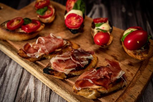 Arrangement of a selection of different tapas or bruschettas on a wooden board. Mediterranean food concept. High view.