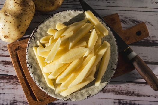 Dish with raw cane potatoes to make french fries. top view. close-up.