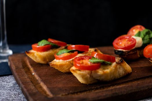 Typical Italian bruschetta or Spanish tapa with cherry tomato, basil and Philadelphia type spreadable cheese. Mediterranean food concept. Copy space.