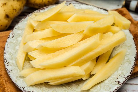 Dish with raw cane potatoes to make french fries. Chopped or high view. close-up.