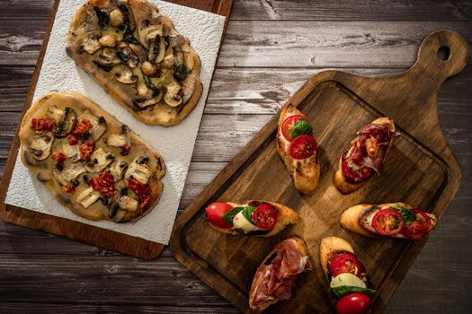 Arrangement of a selection of different tapas or bruschettas on a wooden board. Mediterranean food concept.