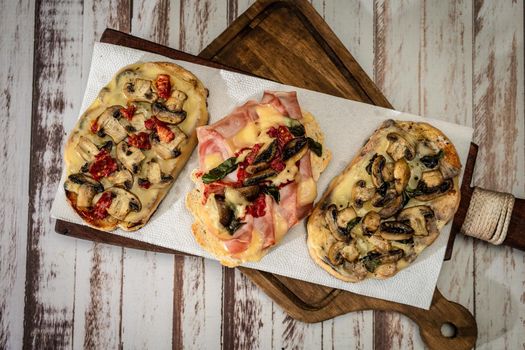 Large bruschettas with cheese, mushrooms, prosciutto and tomato in different combinations. Mediterranean food concept. top view