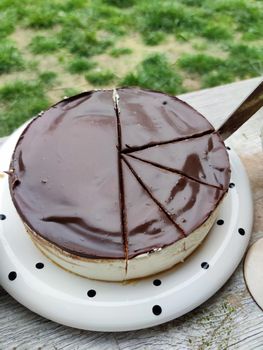 cutting round creamy chocolate cheesecake into pieces close-up