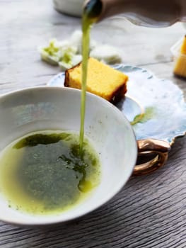 green tea is poured into a cup from a teapot