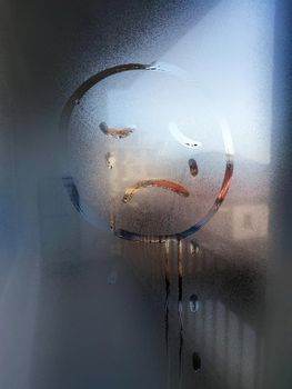 crying sad emoticon painted on misted glass.