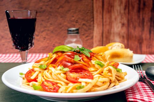 High view of a plate of spaghetti pasta with a delicious tomato sauce with homemade basil leaves. Homemade and natural food concept.