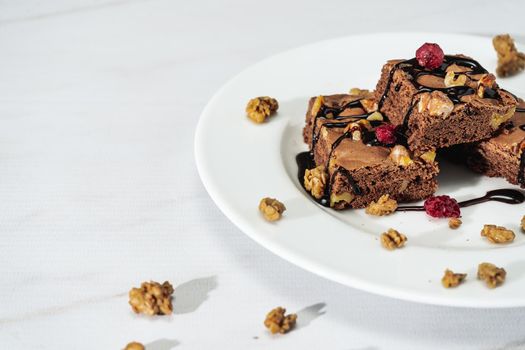 Chocolate brownie squares with walnut pieces, chocolate threads and granola. Natural, healthy food concept. High view. Copy space.
