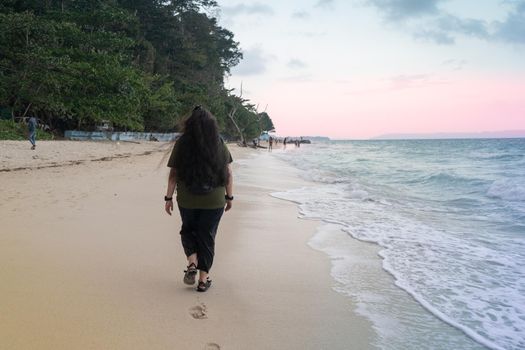 young indian woman walking on kalapathar beach in havelock andaman and nicobar at dusk dawn showing this relaxing tourist destination tropical paradise