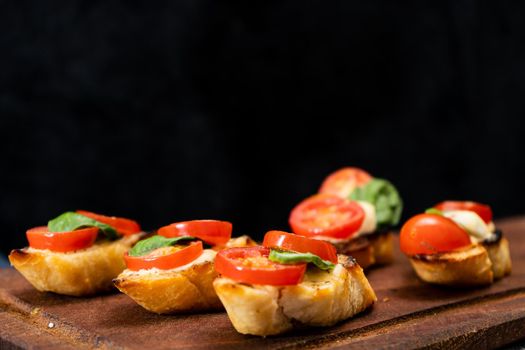 Typical Italian bruschetta or Spanish tapa with cherry tomato, basil and Philadelphia type spreadable cheese. Mediterranean food concept. Copy space.
