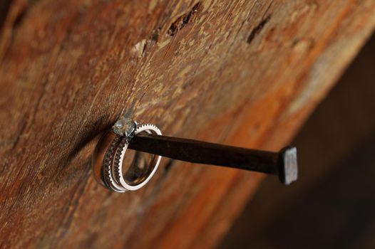 White Gold Silver Platinum and Diamond Wedding and Engagement Rings Threaded on Antique Nail on Wooden Timber Post Beam in House built by Mennonites