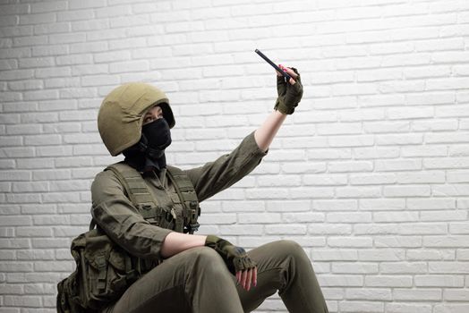 soldier girl in a helmet takes a selfie on a mobile phone