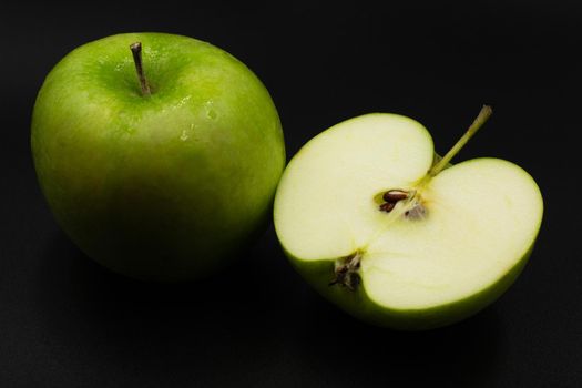 Fresh green apple and sliced isolated on black background art abstract concept.