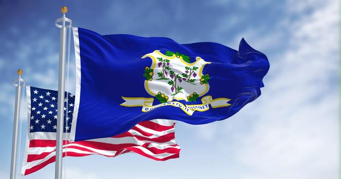 The Connecticut state flag waving along with the national flag of the United States of America. In the background there is a clear sky.