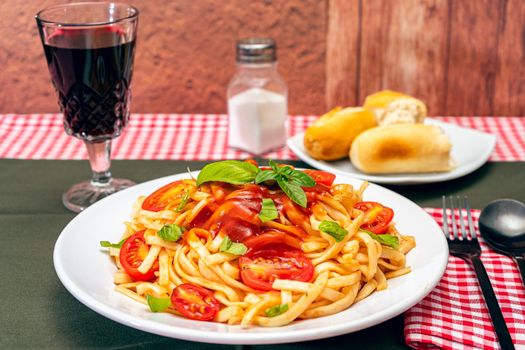 High view of a plate of spaghetti pasta with a delicious tomato sauce with homemade basil leaves. Homemade and natural food concept.