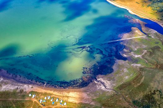 Aerial view from drone of a lakeshore. The water changes color from white, turquoise to navy blue. Serenity and peacefulness