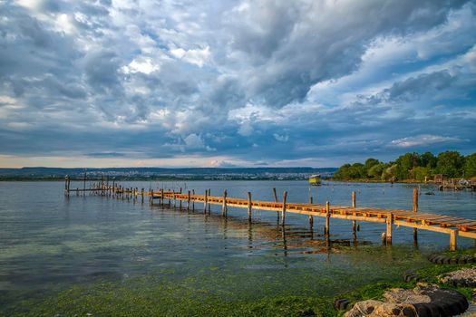 Beauty and calm sunset on the lake with a wooden pier 