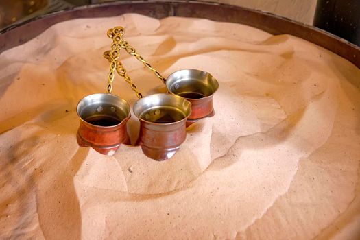 Turkish coffee is made in a traditional way. The copper coffee pots on the hot sand