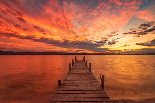 Exciting colorful sunset view from the shore with a wooden pier