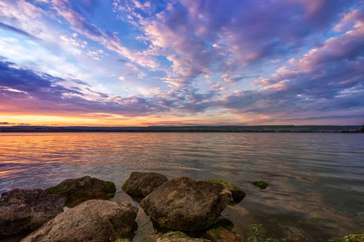 Rocky beach landscape at the lake after sunset.