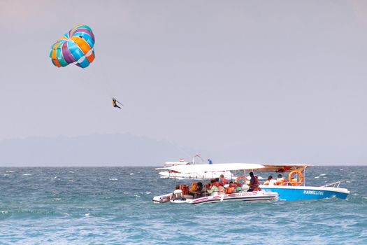 multiple boats in distance doing para gliding sailing while adventure sports like jet sking happening showing busy summer season in goa havelock andaman nicobar island india asia