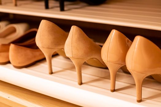 close up fashionable women high heels, leather men shoes and sport shoes in wooden cabinet for going to work