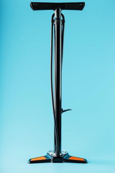 Black bicycle manual air pump for pumping wheels on a blue background with a vertical composition