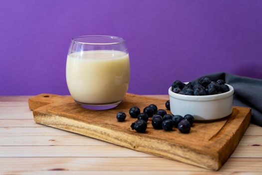 High view of a glass of milk next to some blueberries in a modern, stripped-down setting.