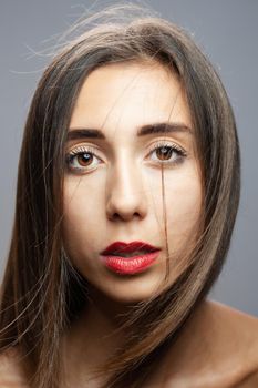 Beautiful brunette girl studio portrait. Serious face expression.