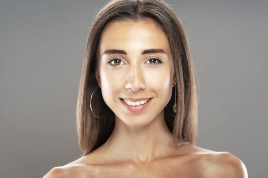 Beautiful brunette girl studio portrait. Smiling face expression.