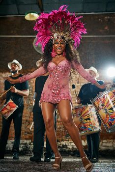 Full length portrait of a beautiful samba dancer performing in a carnival with her band.