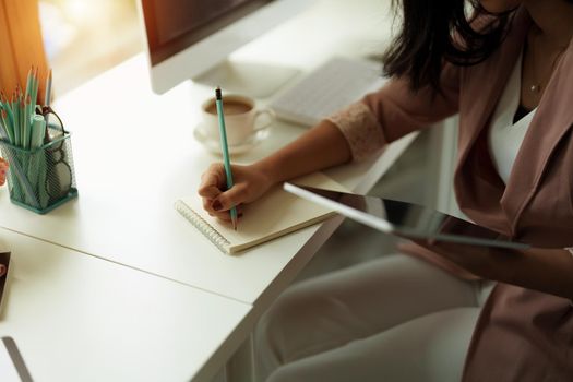 Cropped photo of woman writing making list taking notes in notepad working or learning on laptop indoors- educational course or training, seminar, education online concept.