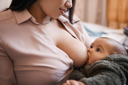 Shot of a young woman breastfeeding her adorable baby on the sofa at home.
