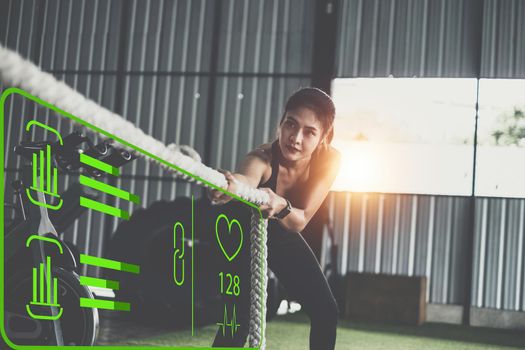 Female working out with battling rope at gym with Virtual Reality Modeling Software Application. Healthy modern people concept