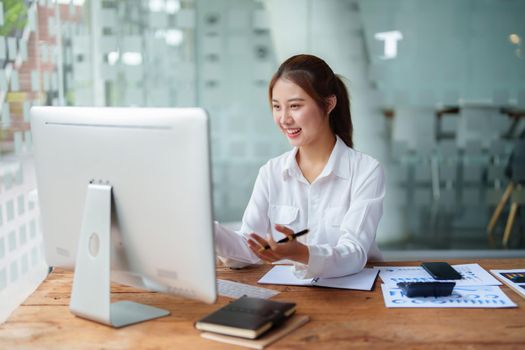 Data analysis, roadmap, marketing, accounting, auditing. Portrait of Asian businesswoman using computer in video conferencing, presenting marketing plan using statistical data sheet at work