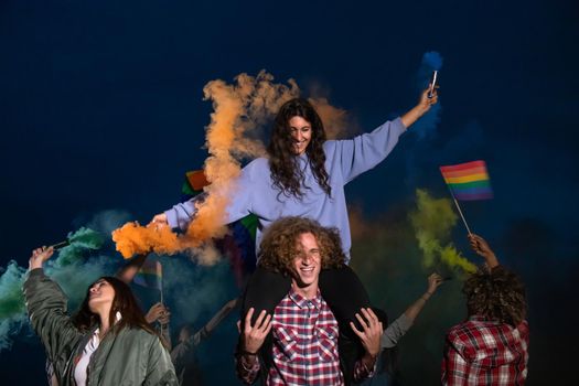 Happy group of people dancing and celebrating LGTB rights want rainbow flag in coloured smoke. Celebration and pride concept.