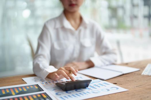 accountant, Auditor, Self-Employed, Finance and Investment, tax calculation and budget, Asian female entrepreneur using a calculator to calculate. Company business results document