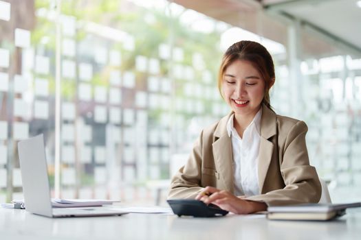 accountant, Auditor, Self-Employed, Finance and Investment, tax calculation and budget, Portrait of Asian female entrepreneur using a calculator to calculate. Company business results document