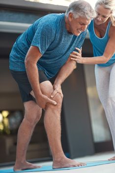 Shot of a mature man grabbing his leg in pain after an intense workout with his wife.