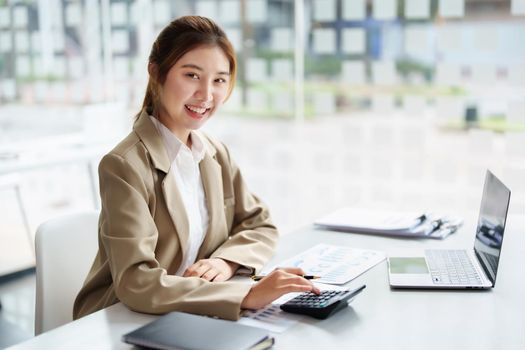 accountant, Auditor, Self-Employed, Finance and Investment, tax calculation and budget, Portrait of Asian female entrepreneur using a calculator to calculate. Company business results document