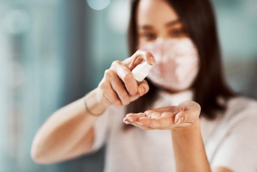 Closeup shot of a businesswoman using hand sanitiser in an office.