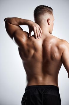 Studio shot of a muscular young man posing against a grey background.