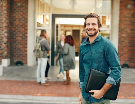 Portrait of a happy young man standing outdoors on campus.