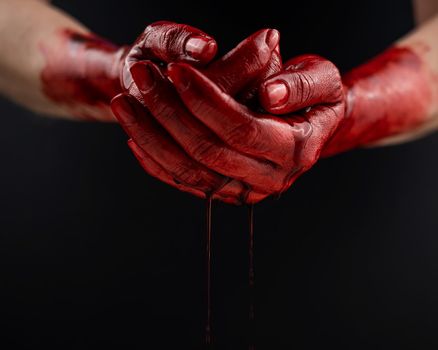 Woman holding blood-stained palms together on black background